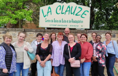 Collaborateurs souriants prennent la pose devant un établissement avant leur visite.