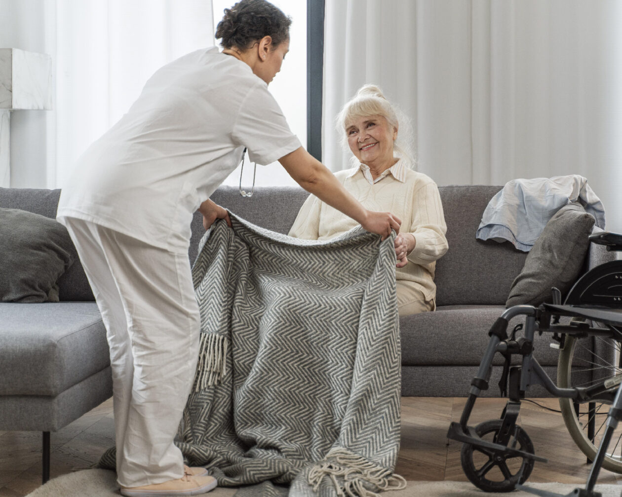 Médecin prend soin d'une personne âgée assise sur un canapé.